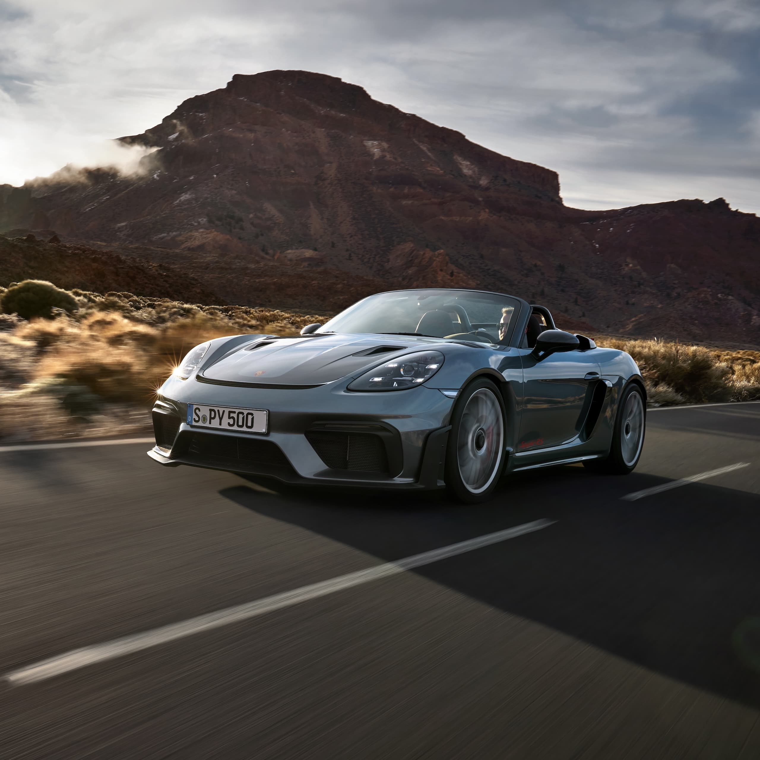 Porsche 718 Spyder RS driving on the road between rock formations.